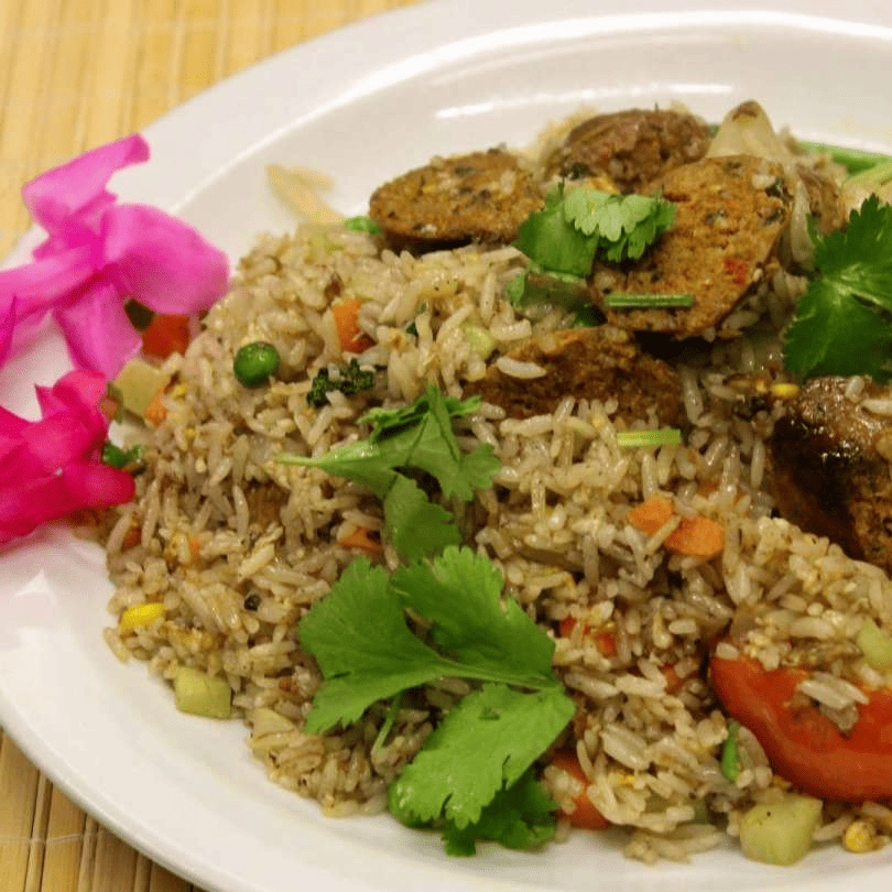 A plate of Chiang Mai Fried Rice garnished with herbs and accompanied by a slice of lime.